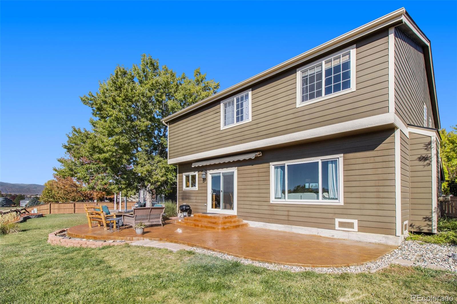 1082 Riddlewood Road Highlands Ranch, CO 80129 - Photo 24 of 28 a backyard of a house with table and chairs and wooden fence