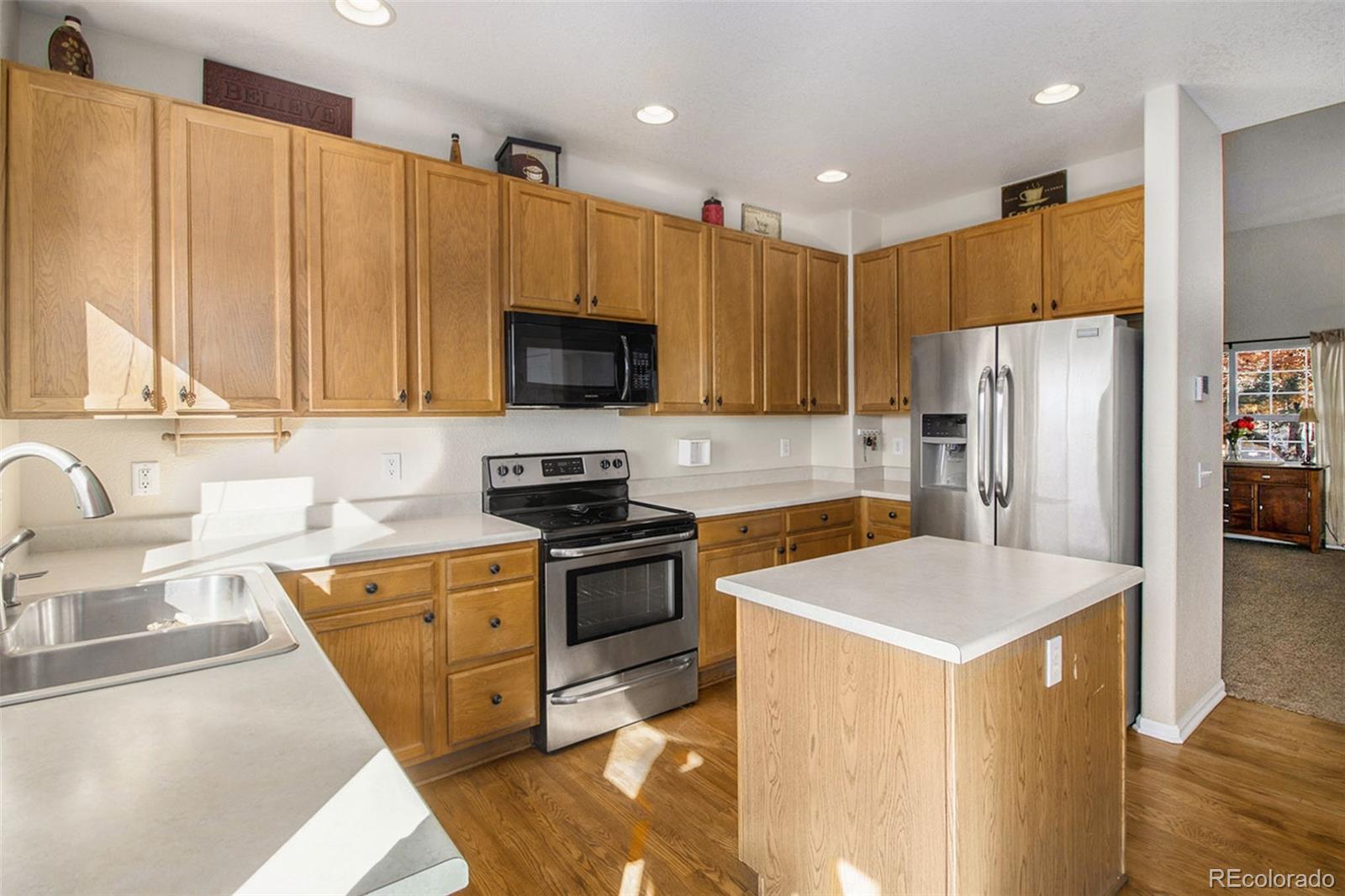 1082 Riddlewood Road Highlands Ranch, CO 80129 - Photo 8 of 28 a kitchen with stainless steel appliances a refrigerator a sink a stove a microwave and cabinets