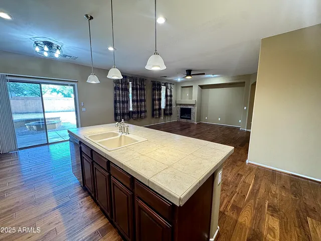 a view of an empty room with wooden floor fireplace and a window