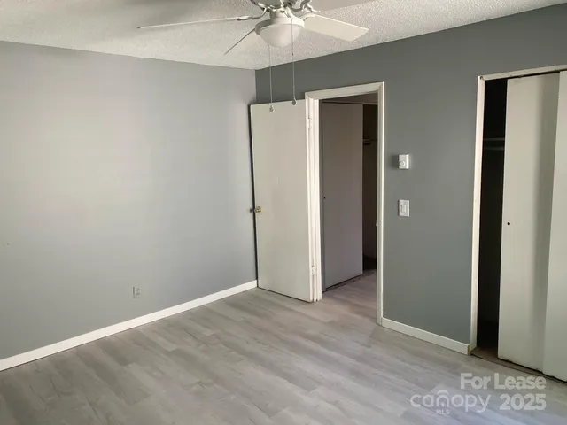 an empty room with a chandelier fan and closet area