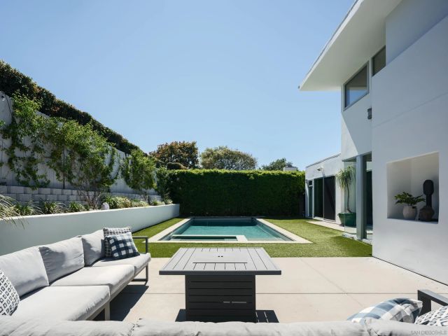a view of swimming pool with seating area and trees in the background