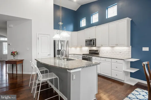 a kitchen with stainless steel appliances granite countertop a stove top oven a sink a dining table and chairs