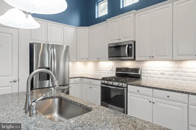 a kitchen with granite countertop a sink stainless steel appliances and cabinets