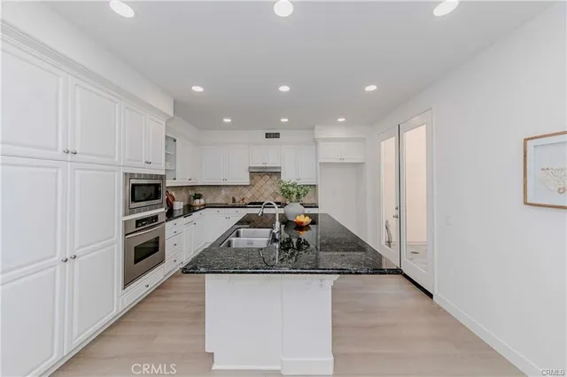 a large kitchen with kitchen island a sink a stove a refrigerator and white cabinets