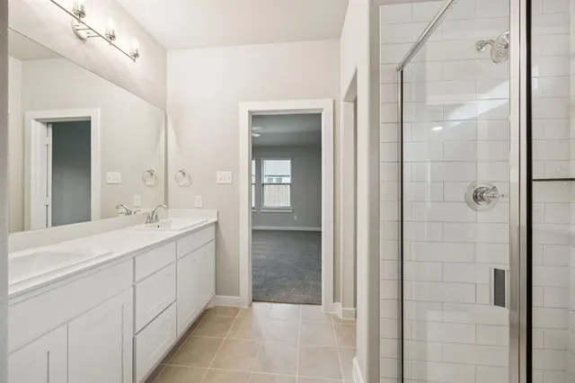 a bathroom with a double vanity sink mirror and shower