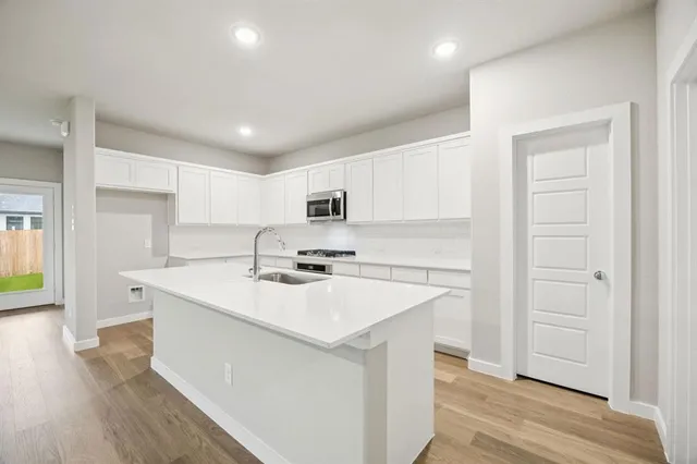 a kitchen with a sink a stove a refrigerator and white cabinets