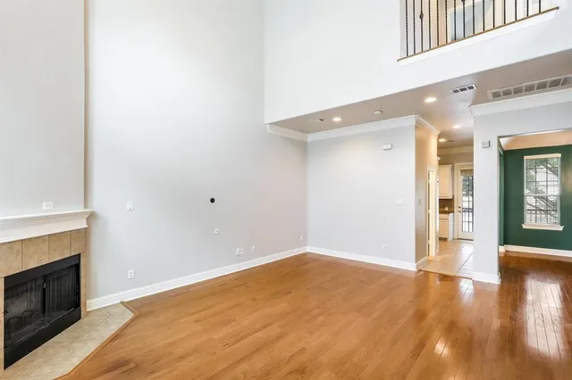 a view of an empty room with wooden floor and a fireplace