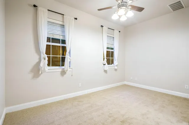 an empty room with windows and fan