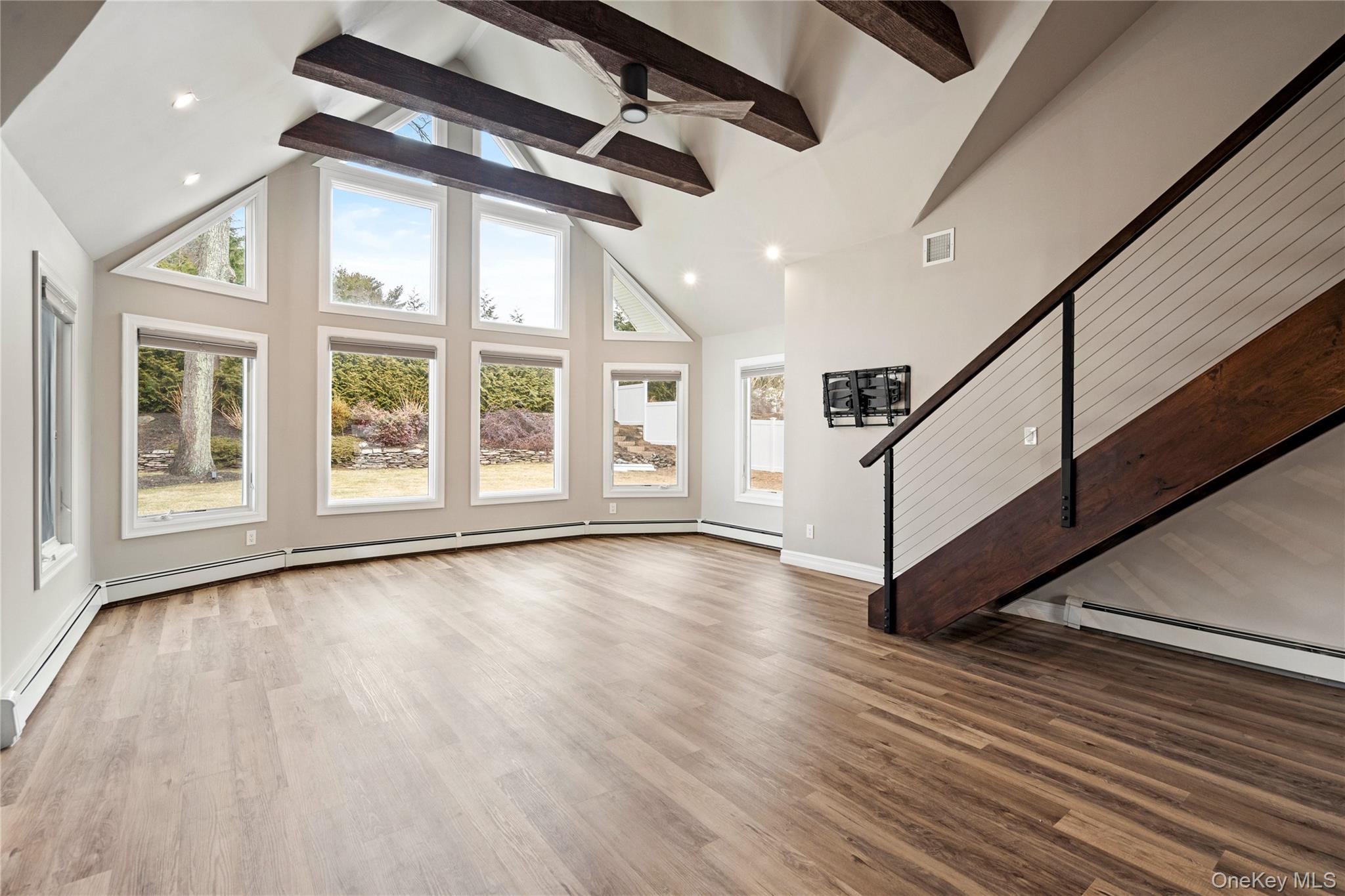 58 Timber Ridge Drive Commack, NY 11725 - Photo 11 of 34 Unfurnished living room featuring light wood-type flooring, high vaulted ceiling, recessed lighting, beamed ceiling, and baseboard heating