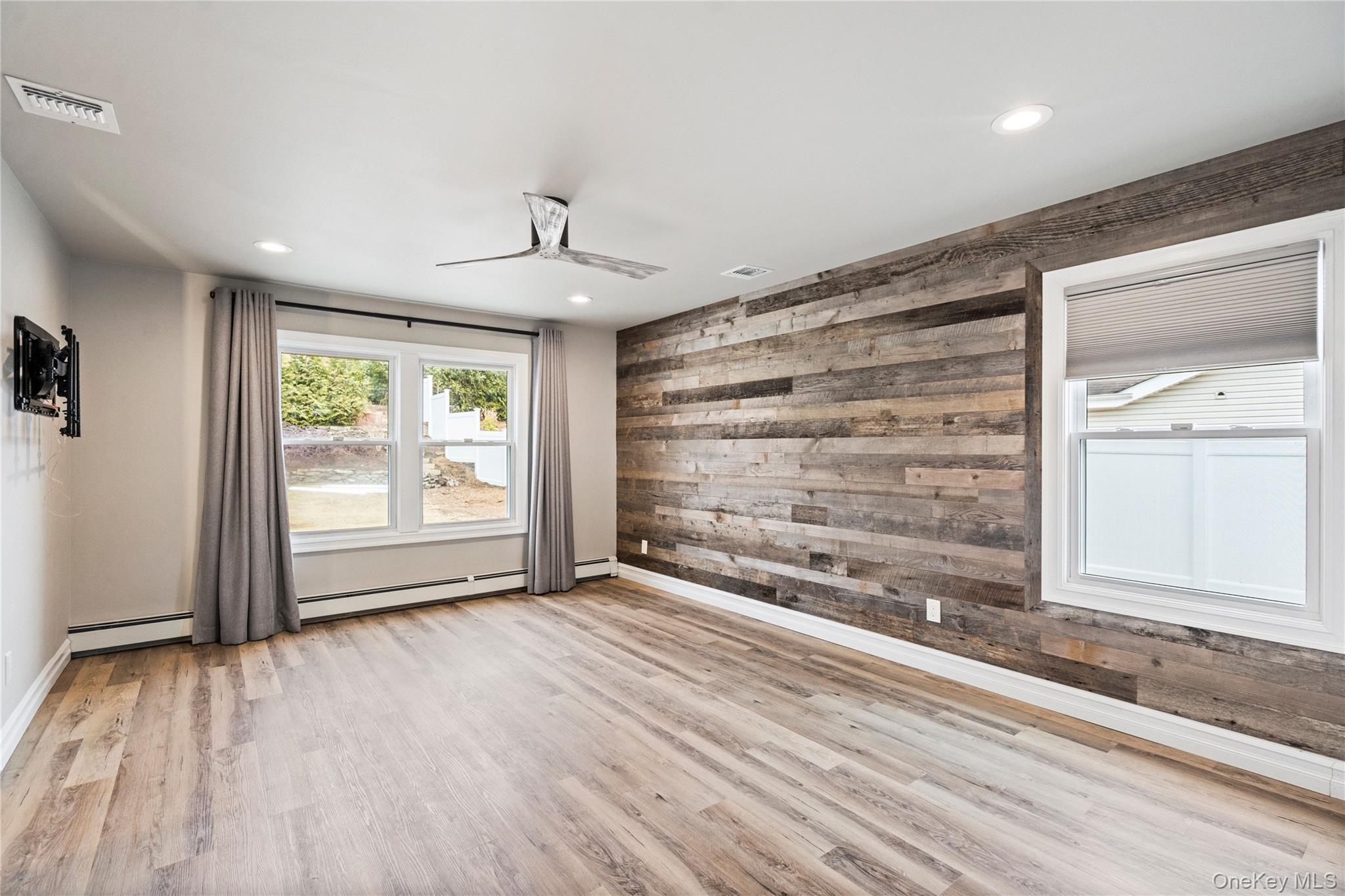 58 Timber Ridge Drive Commack, NY 11725 - Photo 19 of 34 Unfurnished room featuring wooden walls, light wood-style flooring, recessed lighting, and a baseboard radiator