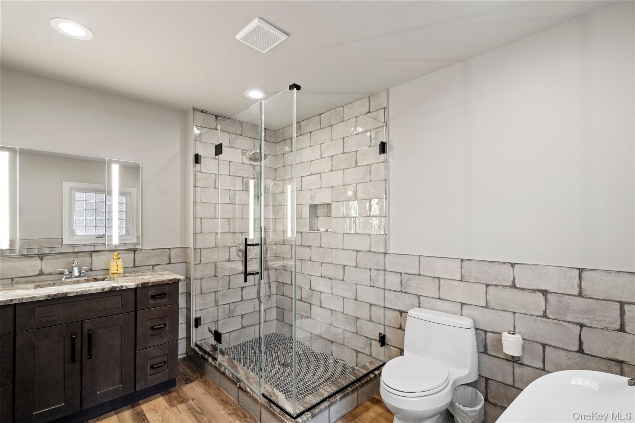 58 Timber Ridge Drive Commack, NY 11725 - Photo 22 of 34 Bathroom featuring tile walls, vanity, a stall shower, a wainscoted wall, and light wood finished floors