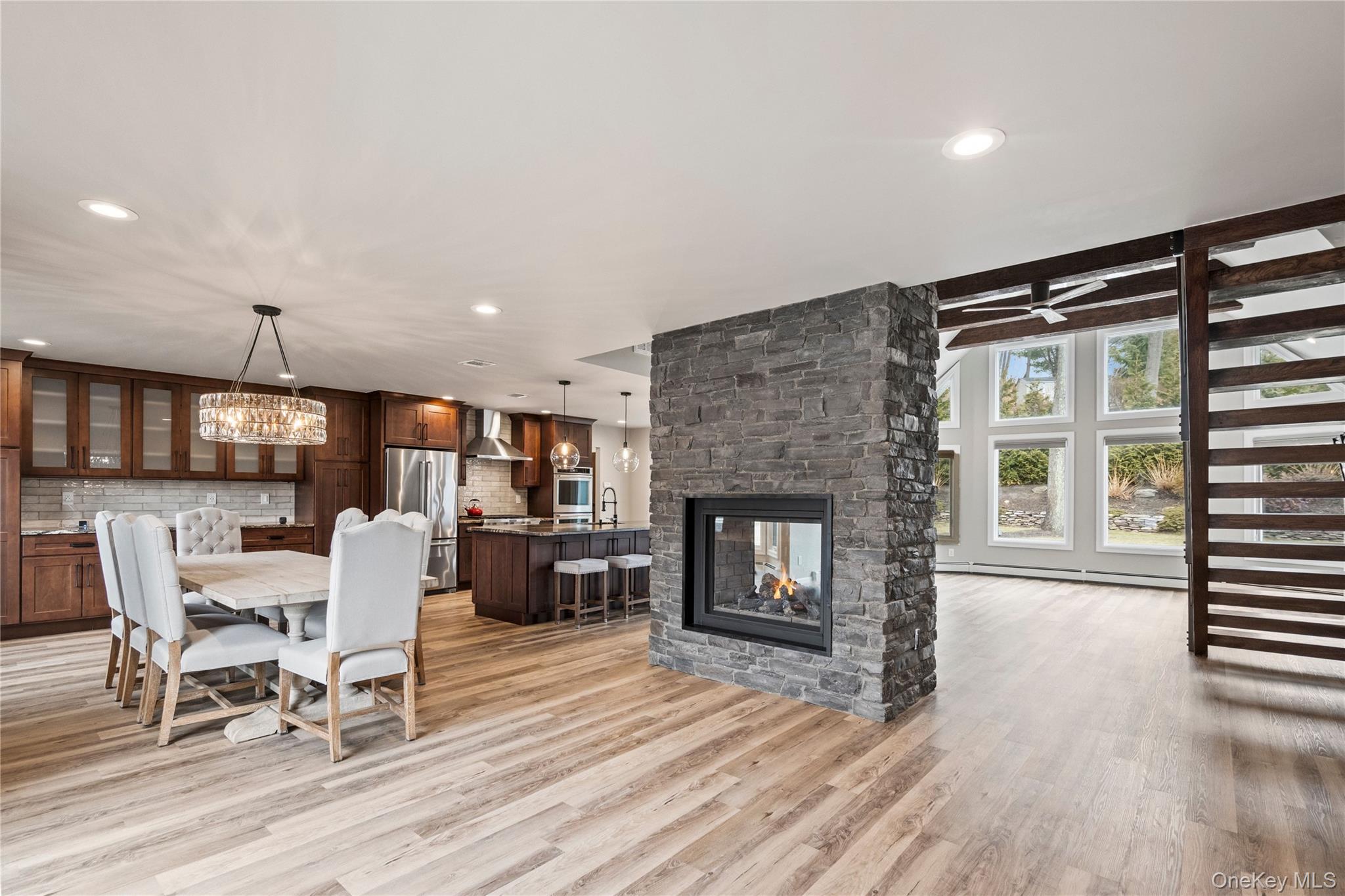 58 Timber Ridge Drive Commack, NY 11725 - Photo 5 of 34 Dining area featuring a fireplace, light wood-type flooring, recessed lighting, a baseboard radiator, and a chandelier