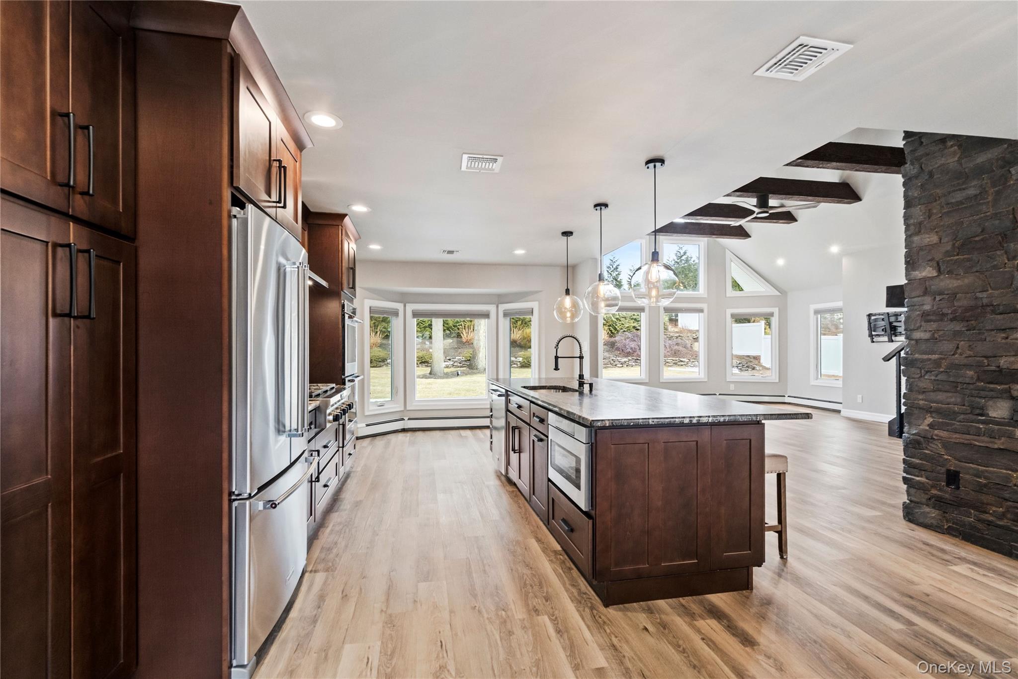 58 Timber Ridge Drive Commack, NY 11725 - Photo 9 of 34 Kitchen with dark brown cabinets, a kitchen breakfast bar, stainless steel appliances, decorative light fixtures, and a center island with sink
