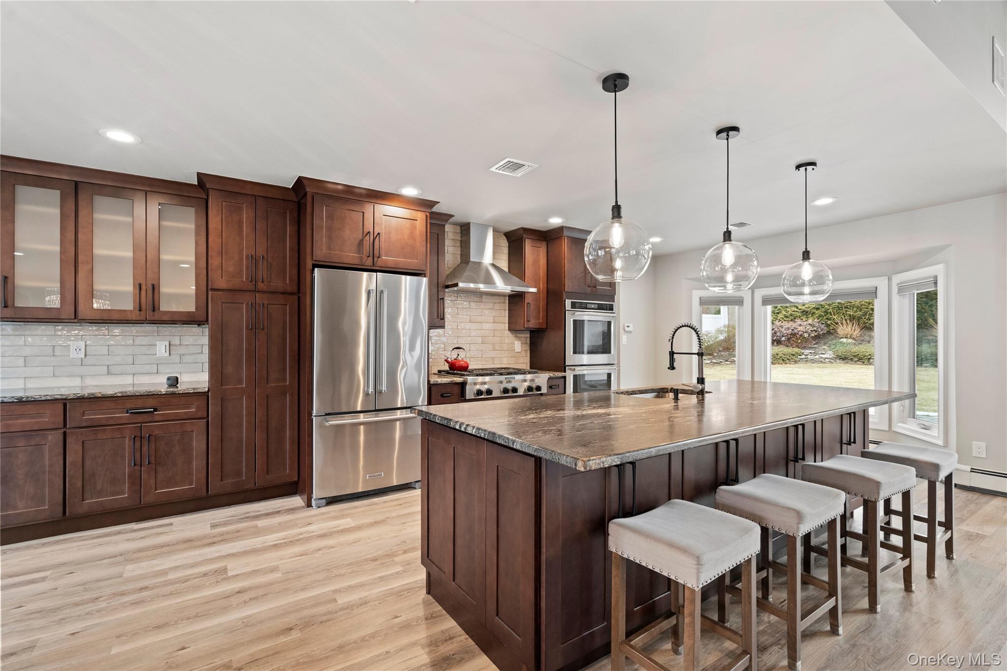 58 Timber Ridge Drive Commack, NY 11725 - Photo 10 of 34 Kitchen featuring appliances with stainless steel finishes, a breakfast bar area, dark stone counters, tasteful backsplash, and glass insert cabinets