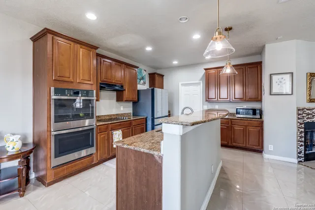 a large kitchen with stainless steel appliances granite countertop a stove a sink dishwasher a microwave oven and a refrigerator with wooden cabinets