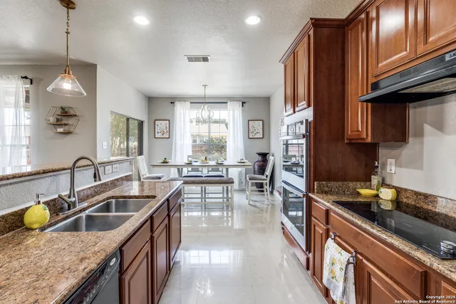 a kitchen with granite countertop a sink a counter space appliances and cabinets