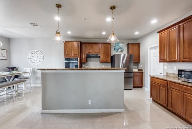 a large kitchen with kitchen island a sink a counter top stainless steel appliances and cabinets