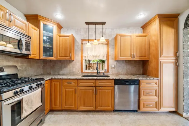 a kitchen with stainless steel appliances granite countertop a stove a sink and a refrigerator