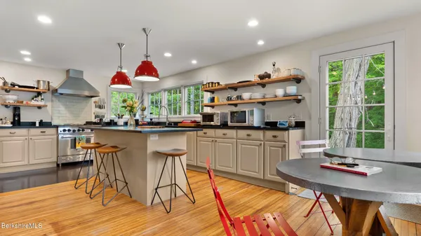 a kitchen with stainless steel appliances granite countertop a stove a sink dishwasher and a dining table with wooden floor