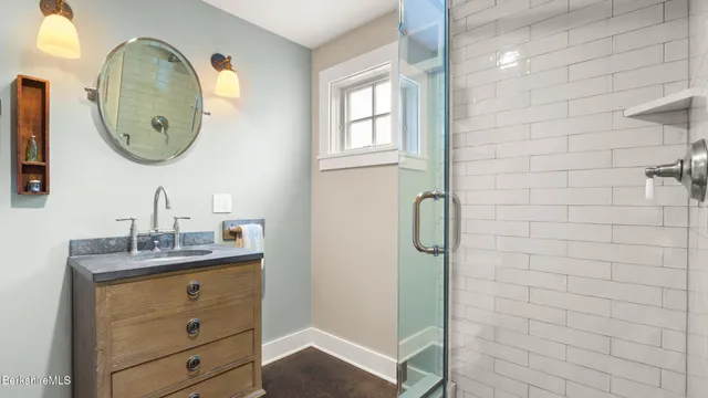 a bathroom with a granite countertop sink a mirror and shower
