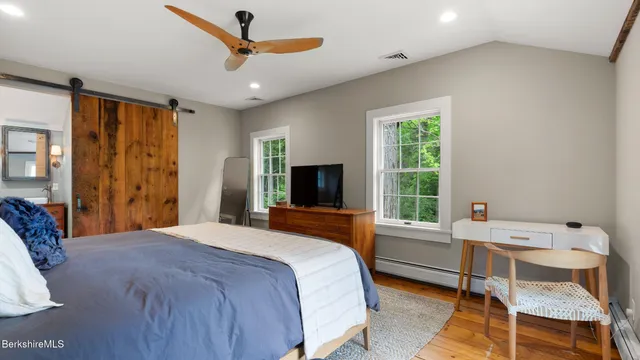 a bedroom with a bed a flat screen tv and a window