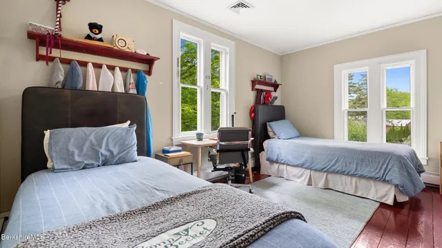 a bedroom with a bed a large window and a potted plant