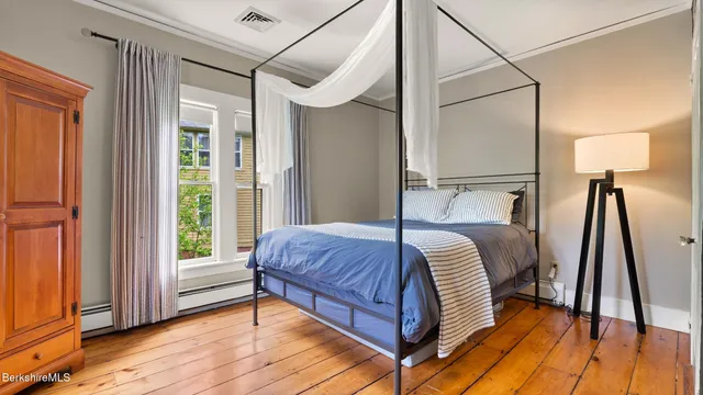 a bedroom with a bed a mirror and a hardwood