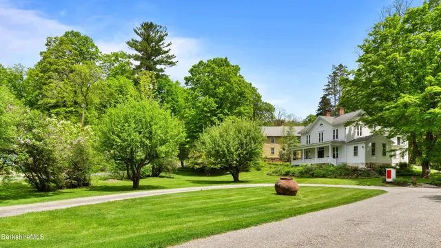 a view of a big house with a big yard and large trees