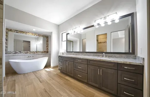 a bathroom with a granite countertop sink a large mirror and a bathtub