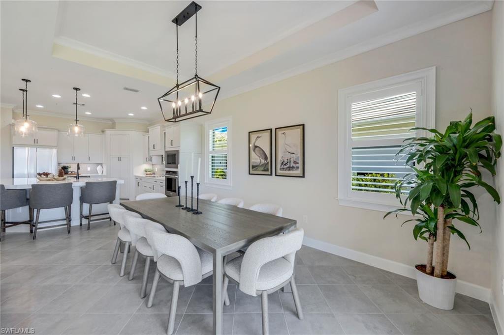 8850 Calypso Court Naples, FL 34113 - Photo 15 of 41 Dining space with a raised ceiling, crown molding, a chandelier, light tile patterned floors, and recessed lighting