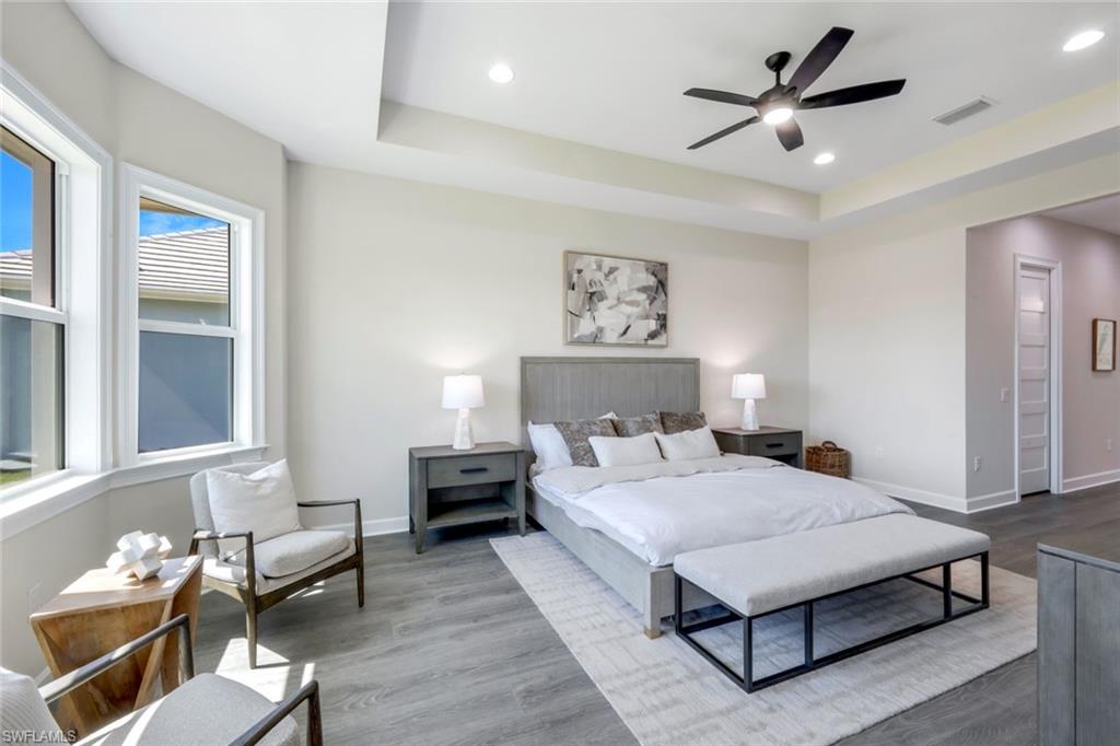 8850 Calypso Court Naples, FL 34113 - Photo 16 of 41 Primary Bedroom Suite featuring a tray ceiling, wood finished floors, a ceiling fan, recessed lighting, and ensuite bath