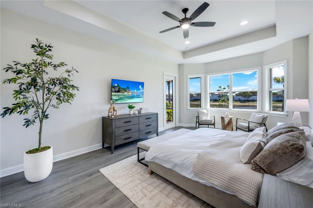 8850 Calypso Court Naples, FL 34113 - Photo 17 of 41 Primary Bedroom Suite with a raised ceiling, access to outside, wood finished floors, ceiling fan, and recessed lighting