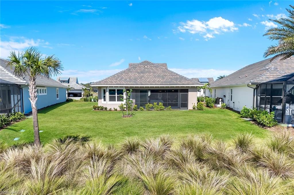 8850 Calypso Court Naples, FL 34113 - Photo 29 of 41 Back of property with a sunroom, a lawn, and stucco siding