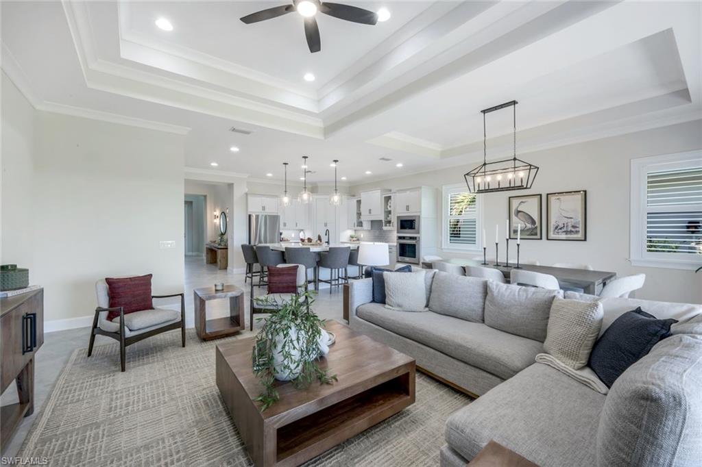 8850 Calypso Court Naples, FL 34113 - Photo 5 of 41 Living room featuring a raised ceiling, recessed lighting, ornamental molding, a chandelier, and ceiling fan