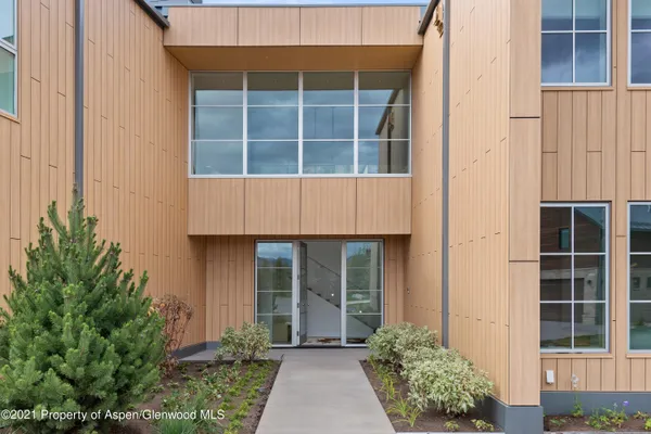 a front view of a house with glass windows and plants