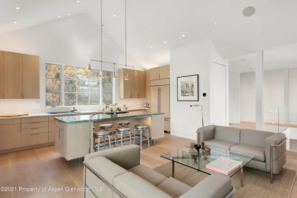 a large kitchen with stainless steel appliances kitchen island granite countertop a living room filled with furniture