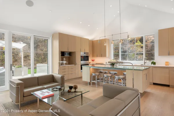 a living room with stainless steel appliances kitchen island granite countertop a couch a stove and a dining table with wooden floor