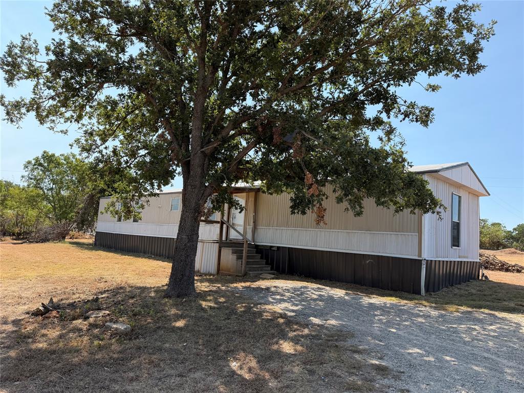 Residence with metal siding, gabled roof, and a gravel driveway
