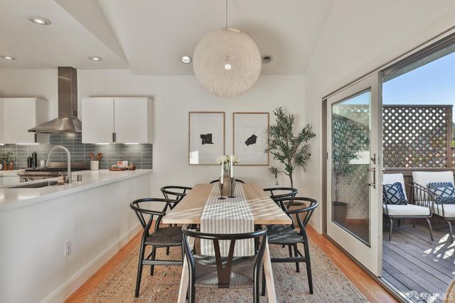 a kitchen with a stove a sink and white cabinets with wooden floor