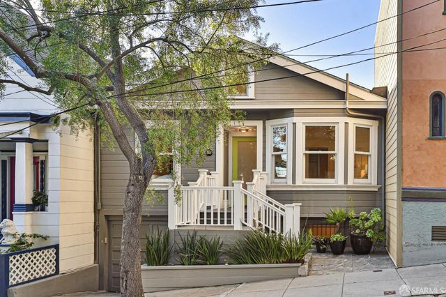 a view of a brick house with large windows and plants