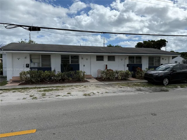 a front view of a house with lots of windows and plants