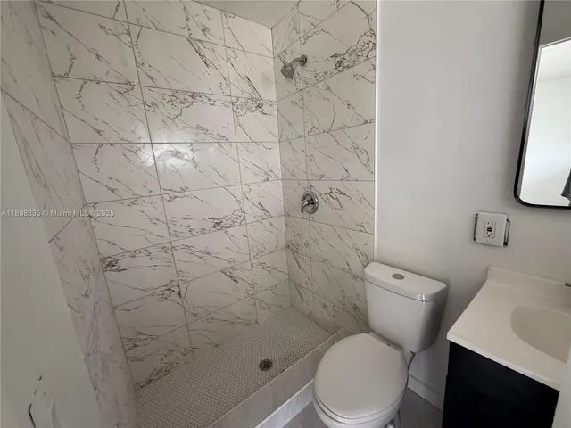 a white toilet sitting next to a white sink and vanity