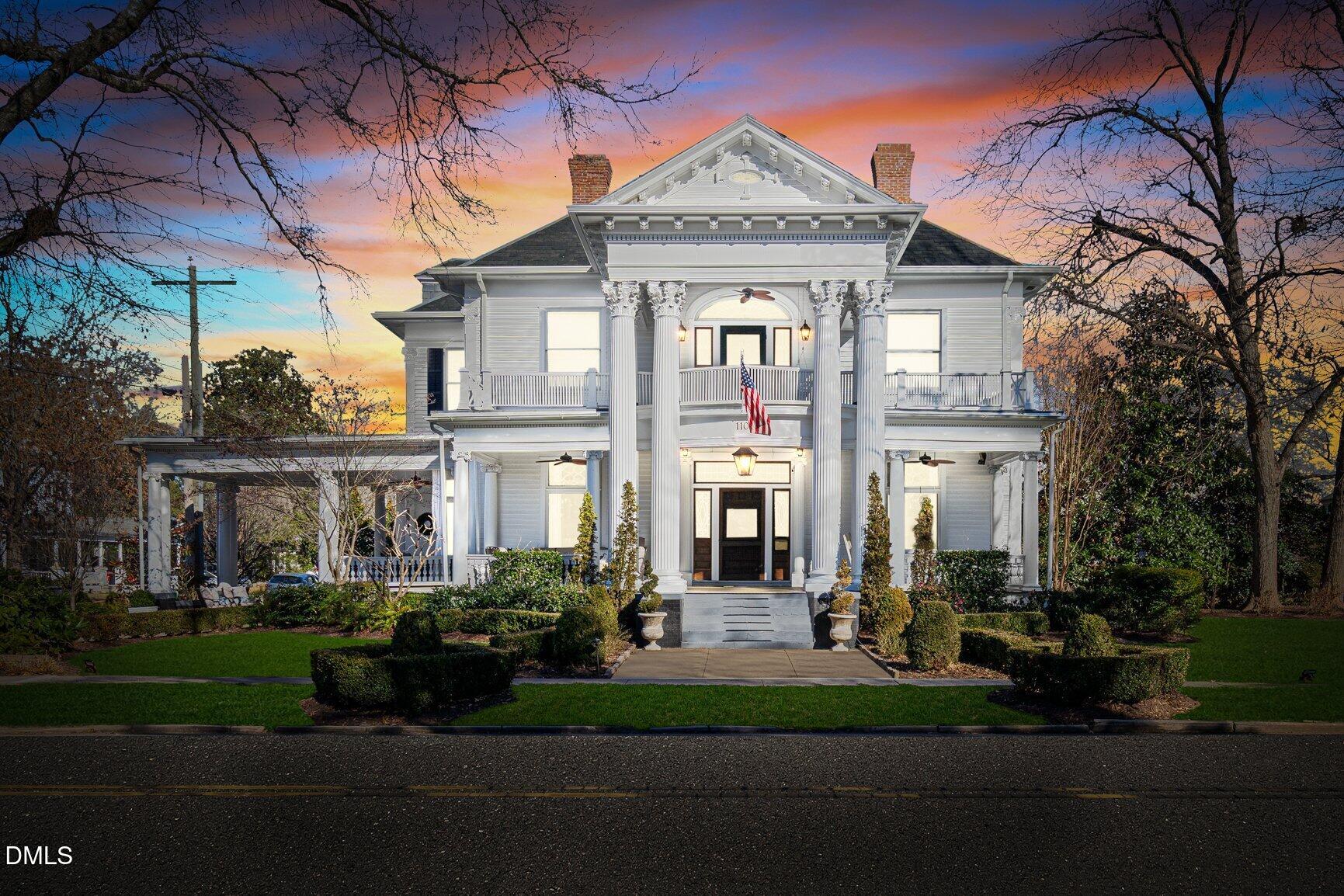 a front view of a house with a garden and trees