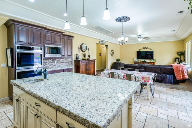 3683 South 2640 West St. George, UT 84790 - Photo 15 of 41 Kitchen island featuring a light-toned granite countertop with an undermount sink and a gooseneck faucet