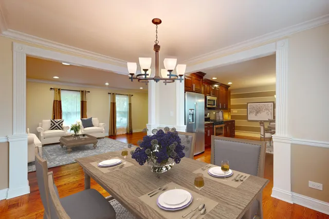 a dining room with wooden floor a chandelier a wooden table and chairs