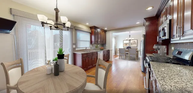 a kitchen with stainless steel appliances granite countertop sink refrigerator dining table and chairs