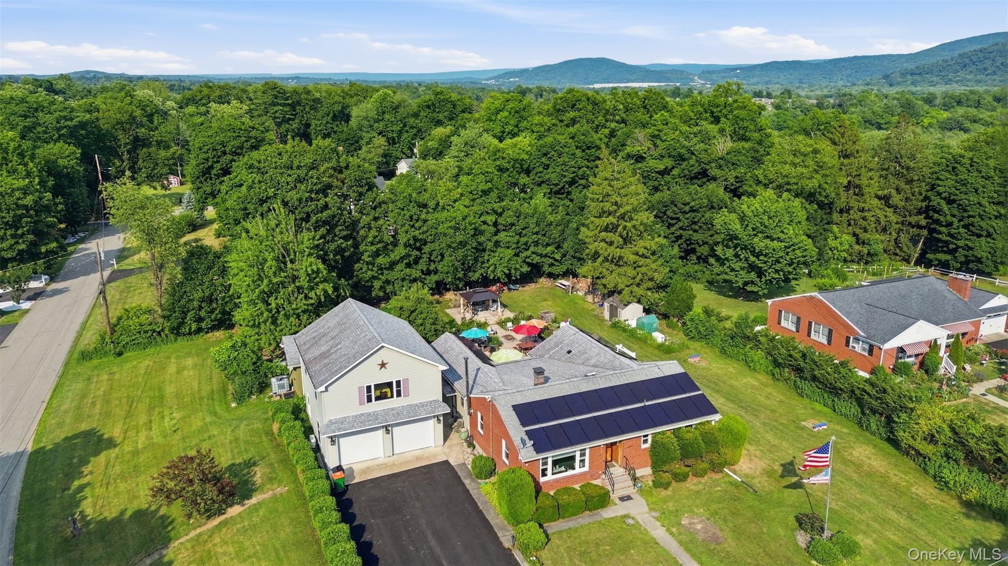 1 Hiko Place Fishkill, NY 12524 - Photo 5 of 41 Brick residence featuring solar panels, a gabled roof, and a mature tree-lined setting