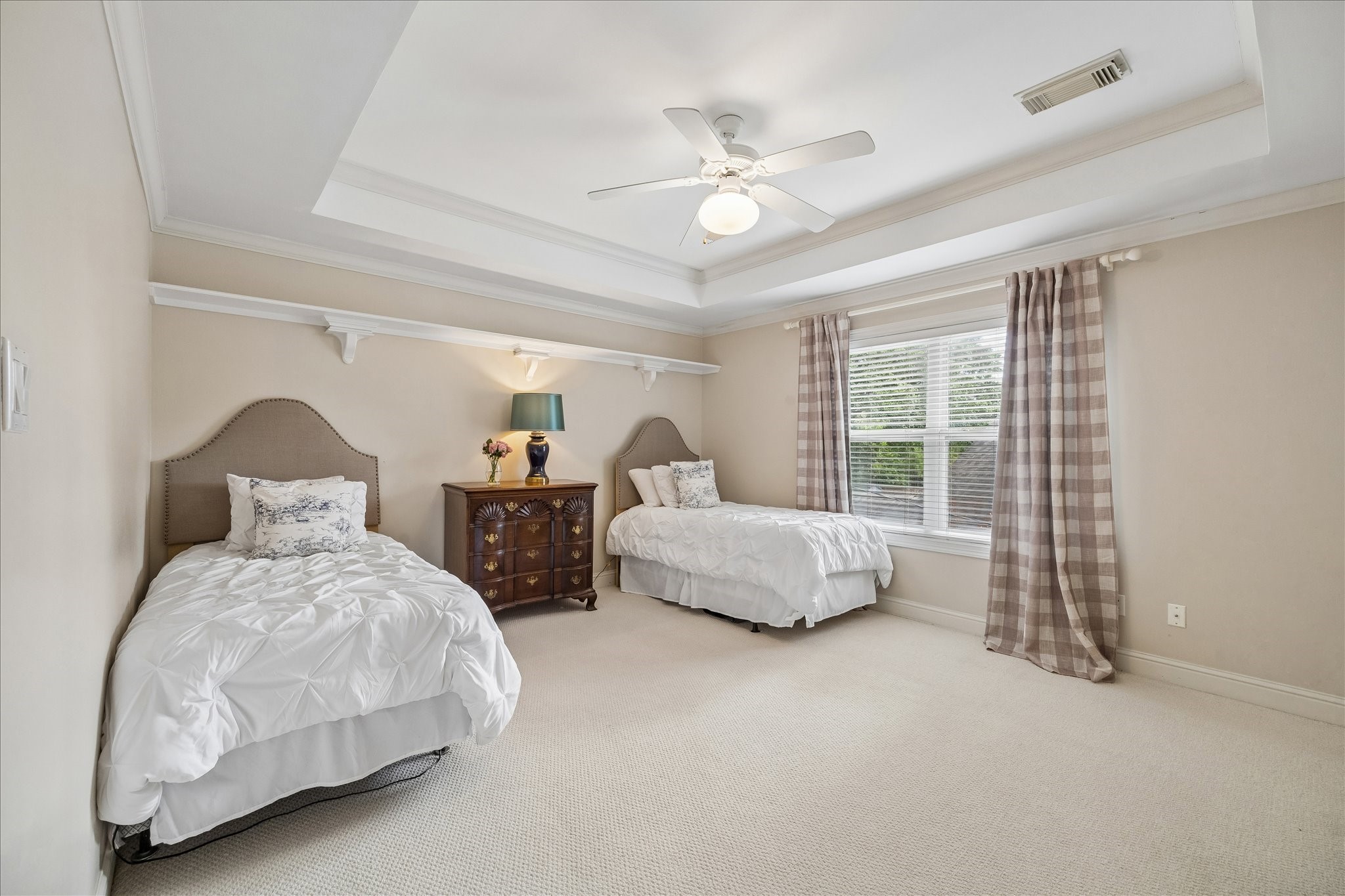11421 Whippoorwill Road Houston, TX 77024 - Photo 18 of 33 Large upstairs bedroom featuring an elegant tray ceiling and integrated crown molding. This bright space includes a private en-suite bath, plush carpeting, and a large window. Perfectly sized for a variety of layouts, from a shared bedroom to a sprawling guest wing.