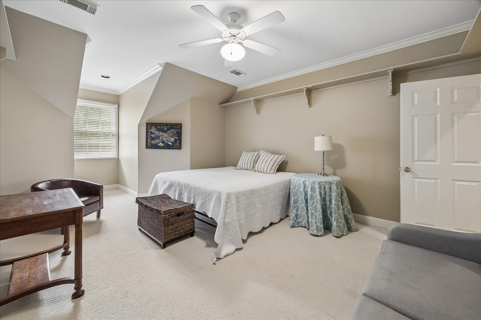 11421 Whippoorwill Road Houston, TX 77024 - Photo 20 of 33 Charming upstairs secondary bedroom featuring unique architectural dormer details and a deep window alcove. This cozy yet spacious retreat includes plush carpeting, a neutral color palette, and custom wall shelving, making it an ideal space for a nursery, hobby room, or quiet guest quarters.