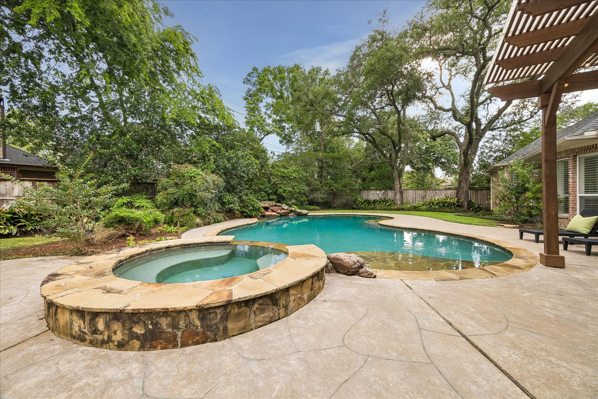 11421 Whippoorwill Road Houston, TX 77024 - Photo 24 of 33 Step into your own private paradise! This resort-style backyard features a sparkling pool with a beach entry and a elevated stone-wrapped spa. Surrounded by lush, mature landscaping and a sprawling flagstone-accented deck, this tranquil oasis offers total privacy and the perfect setting for summer relaxation.